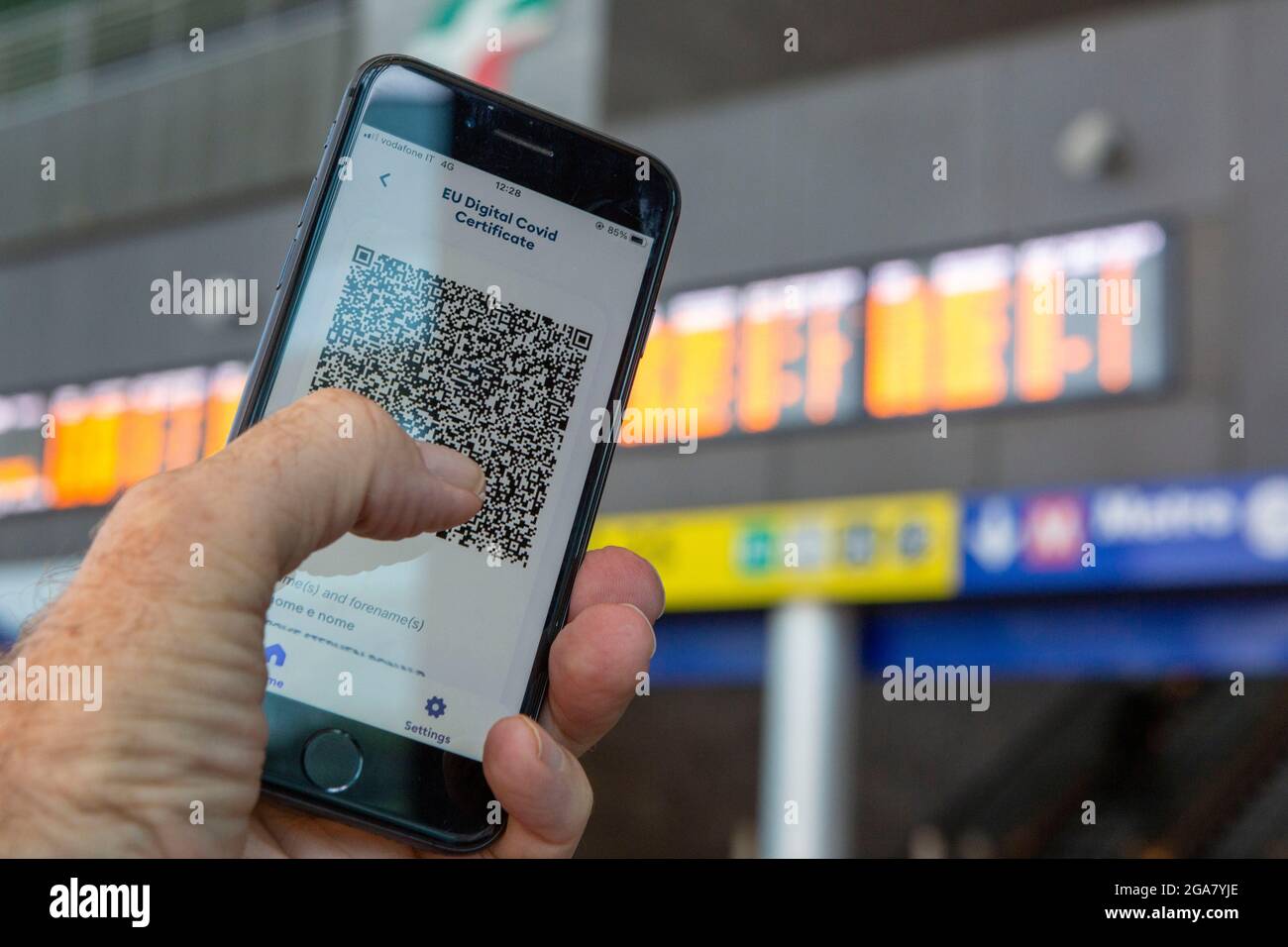 Rom, Italien, Donnerstag, 29. Juli 2021. EU-digitales Covid-Zertifikat Green Pass auf Smartphone vor Zugfahrplänen Stockfoto