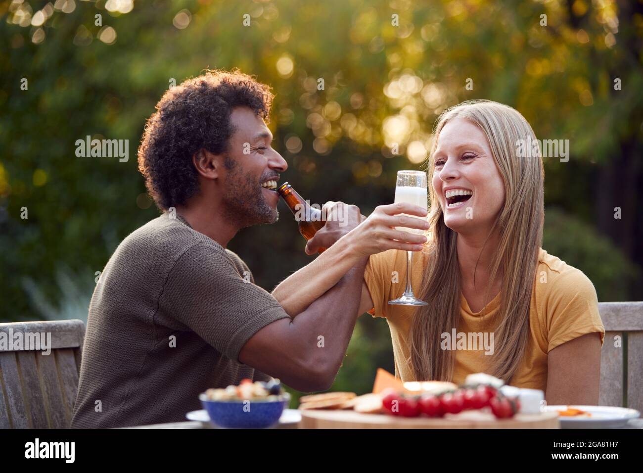 Reifes Paar Link Arms Feiern Mit Bier Und Champagner Am Tisch Im Garten Mit Snacks Stockfoto