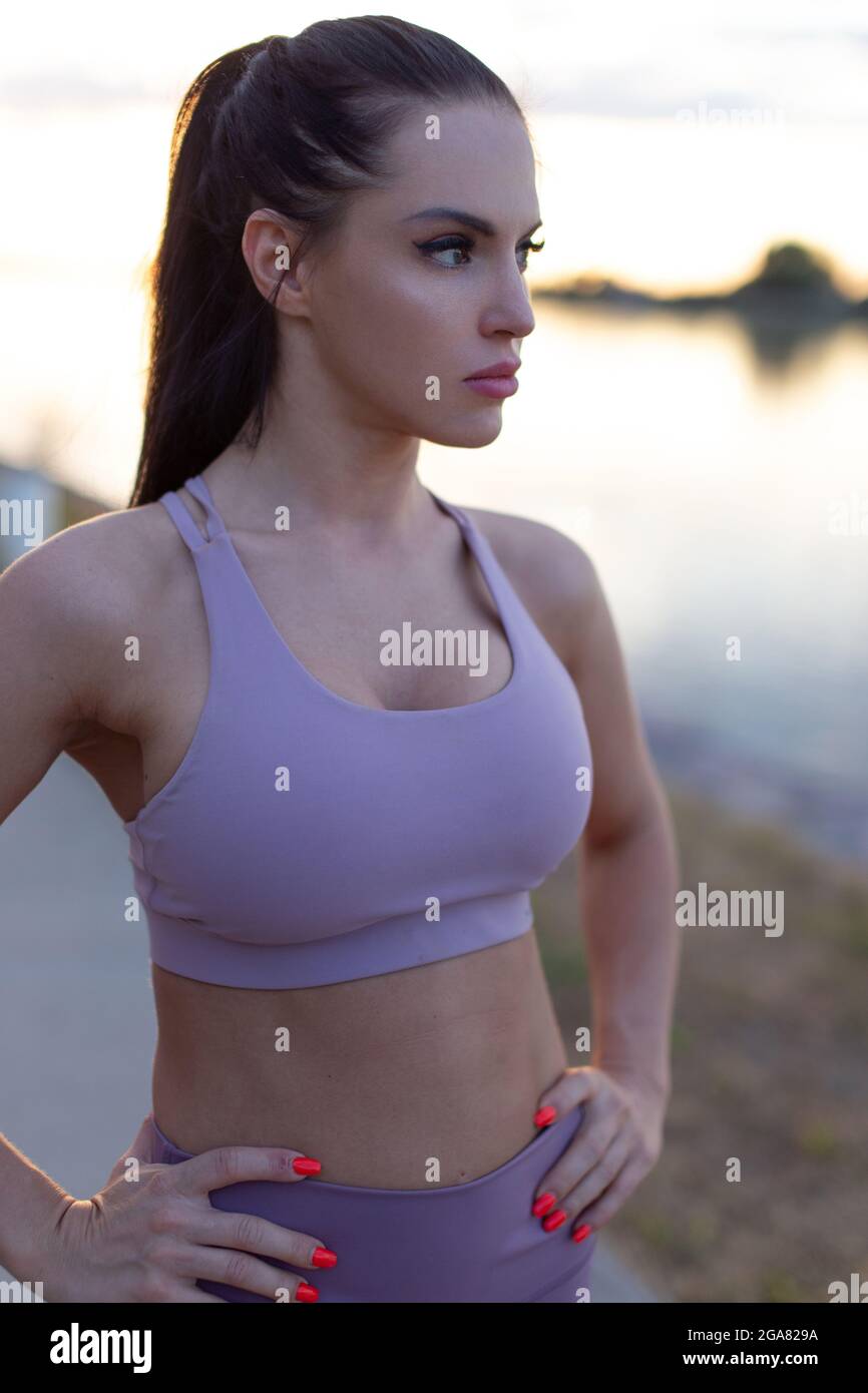 Junge Frau in Sportkleidung, die am Fluss ruht, inneres Gleichgewicht Stockfoto