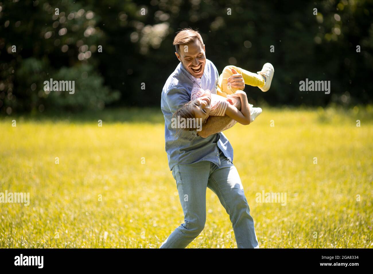 Vater mit niedlichen kleinen Tochter Spaß auf dem Gras im Park Stockfoto
