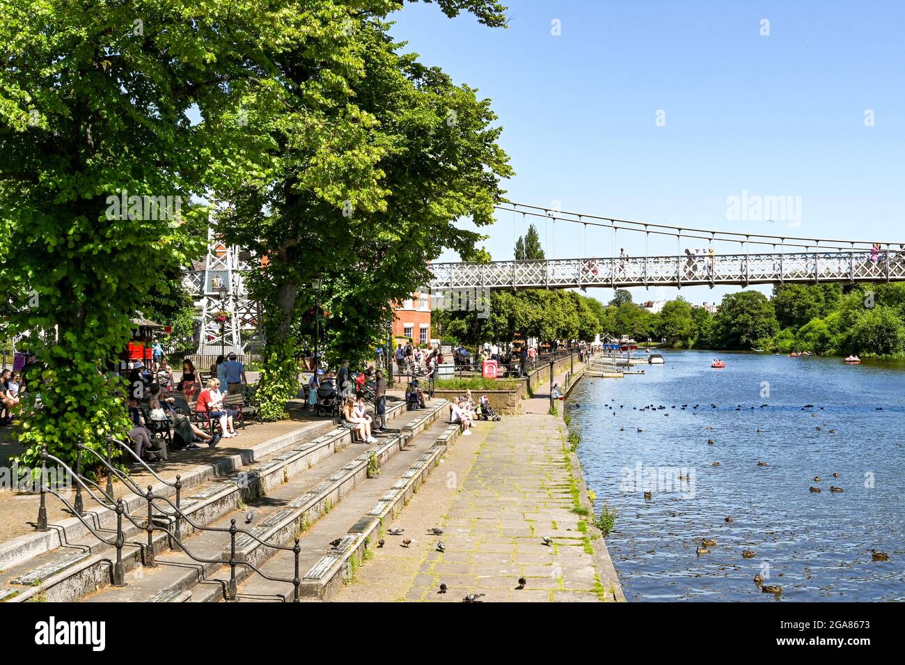 Chester, Cheshire, England - Juli 2021: Menschen, die am Ufer des Flusses Dee sitzen, der durch das Zentrum von Chester fließt Stockfoto