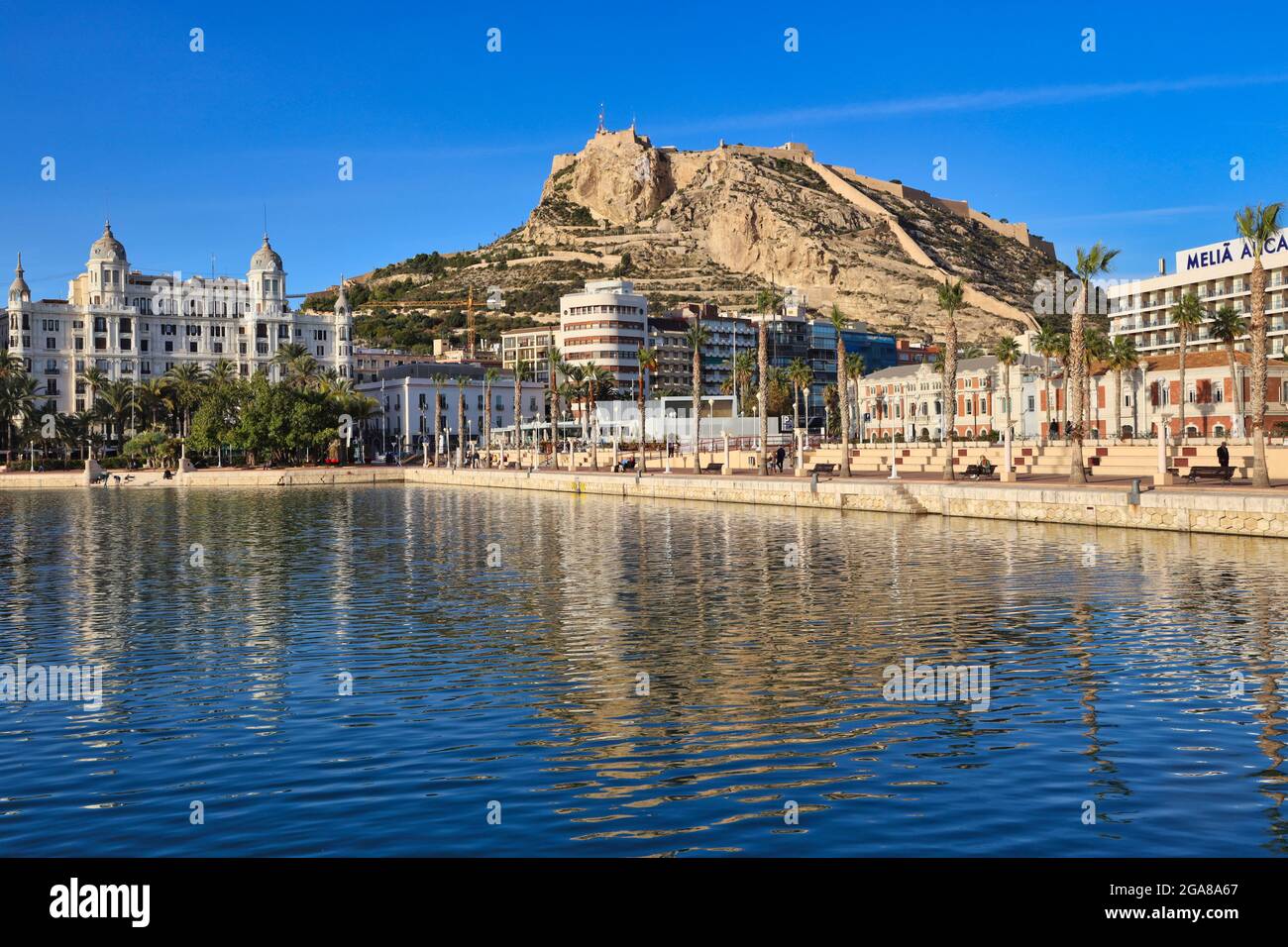 Die Burg von Santa Barbara hoch oben auf einem Vorgebirge mit Blick auf die Stadt Alicante, Spanien, mit der Promenade und dem Wasser im Vordergrund Stockfoto