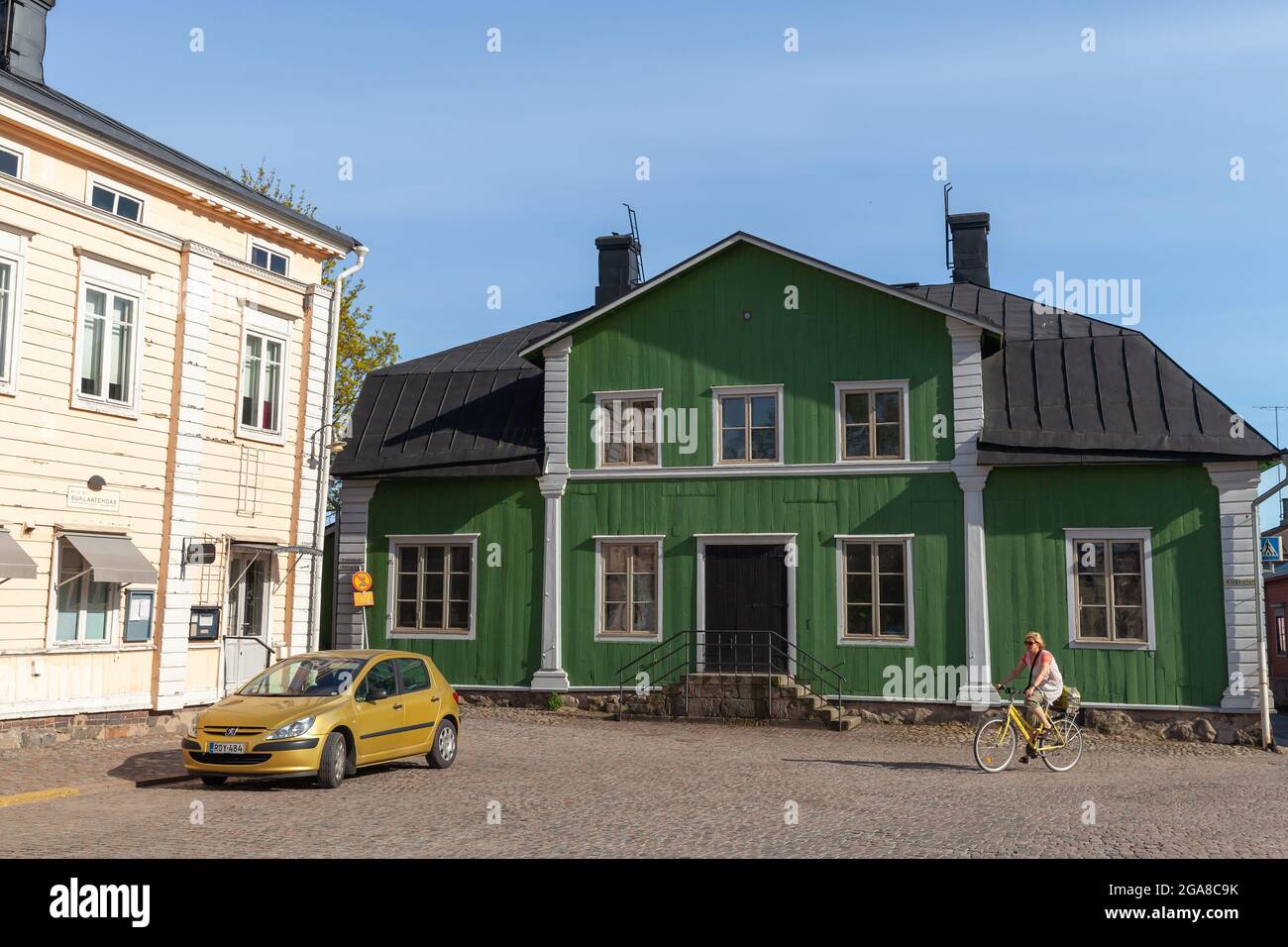 Porvoo, Finnland - 7. Mai 2016: Blick auf die Straße mit bunten finnischen Holzhäusern, Altstadt von Porvoo, Frauen fahren Fahrrad Stockfoto