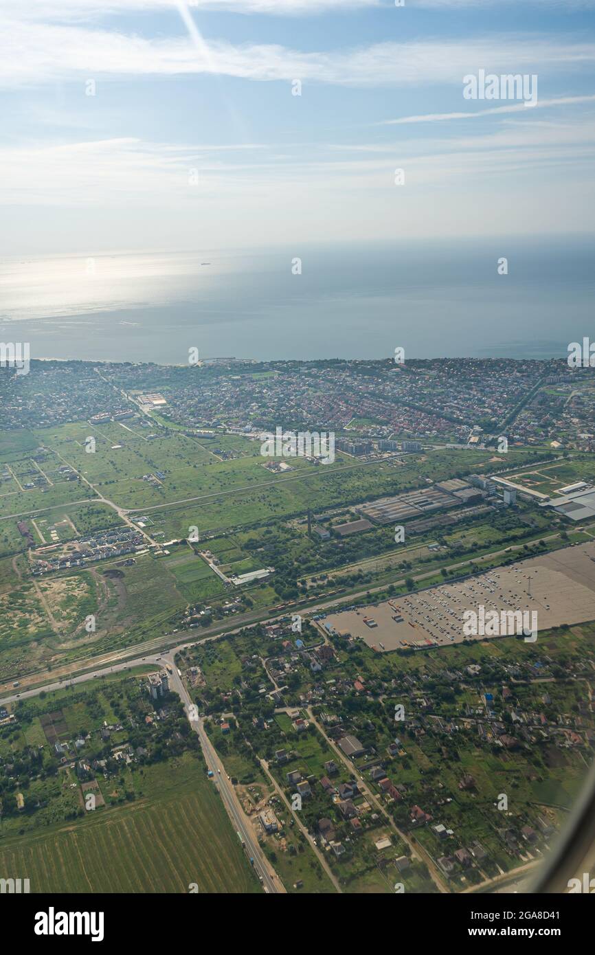 Blick auf das Land durch das Flugzeugfenster. Felder, Straßen, Flüsse aus der Vogelperspektive. Bullauge. Schauen Sie aus dem Fenster eines fliegenden Flugzeugs. Draufsicht auf den Stockfoto