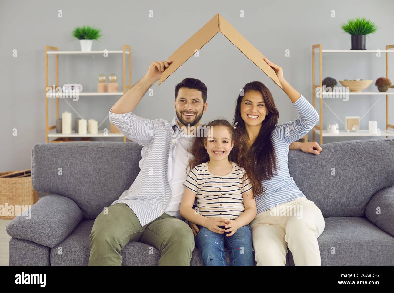 Porträt einer glücklichen jungen europäischen Familie mit Tochter unter Dach entspannen Feiern Sie den Umzug in das eigene Zuhause. Stockfoto