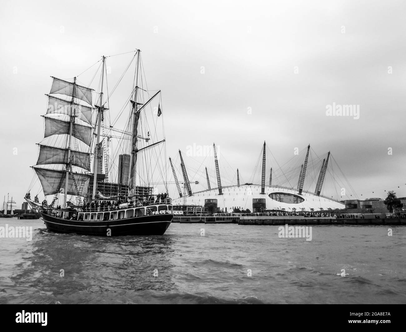 Ein dreimastiger Hochschiff auf der Themse im Großraum London, Großbritannien, mit der O2-Kuppel im Hintergrund, in Schwarz und Weiß. Fotografiert während des Th Stockfoto