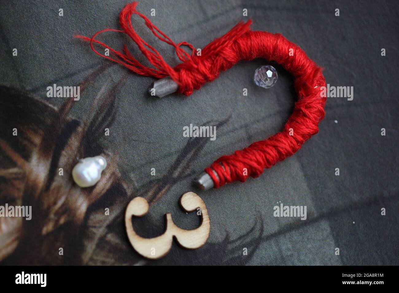 Mixed Media Collage - Creative / Conceptual - Red Threaded Magnet, Flyaway Haar, neben Nummer drei und Perlen Stockfoto