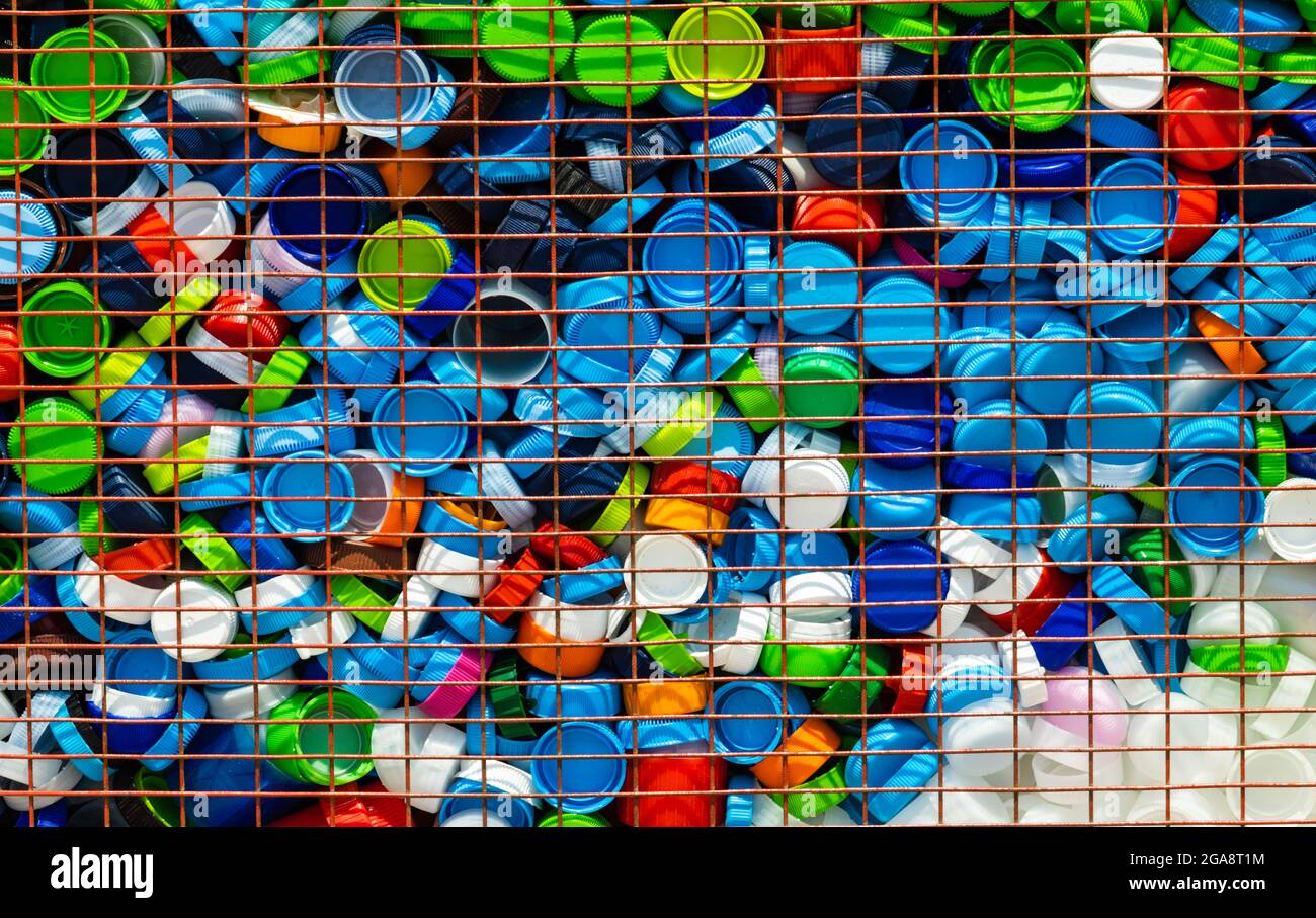 Mehrfarbige Kunststoffkappen aus Kunststoffverpackung in eine Metall-Recycling-Box eingesetzt Stockfoto
