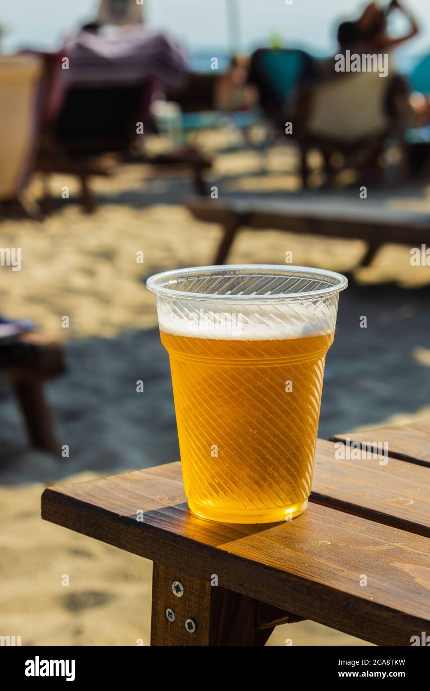 Bier in einem durchsichtigen Plastikglas, das an einem sonnigen Sommertag auf was gelegt wird Stockfoto