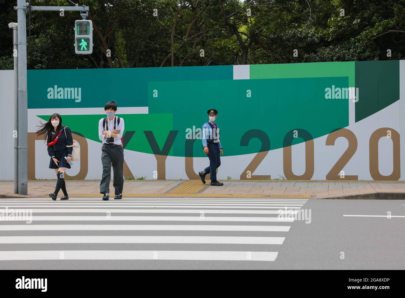 Tokio, Japan. Juli 2021. Besucher des Odaiba Beach überqueren die Straße mit dem Odaiba Marine Park, einem Sportplatz für die Olympischen Spiele 2020 in Tokio für Triathlon und Marathon Schwimmen im Hintergrund am 7. Tag der Olympischen Spiele 2020 in Tokio. (Foto: Stanislav Kogiku/SOPA Images/Sipa USA) Quelle: SIPA USA/Alamy Live News Stockfoto