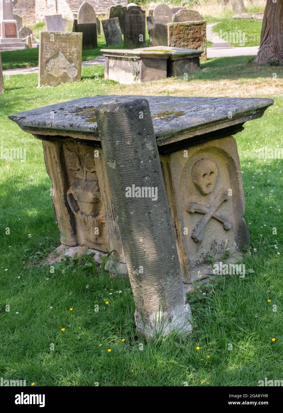 Ein unverwechselbares Denkmal in Form eines Schädels und Kreuzknochen im Pestdorf Eyam in Derbyshire. Stockfoto