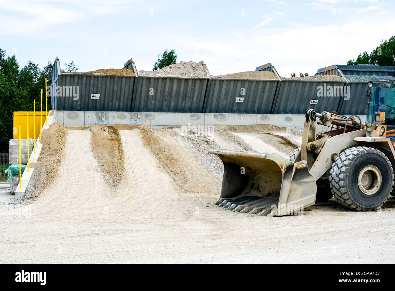 Materialfraktionen unterschiedlicher Größen in Tanks in einer Betonproduktionsanlage, Frontlader im Vordergrund Stockfoto