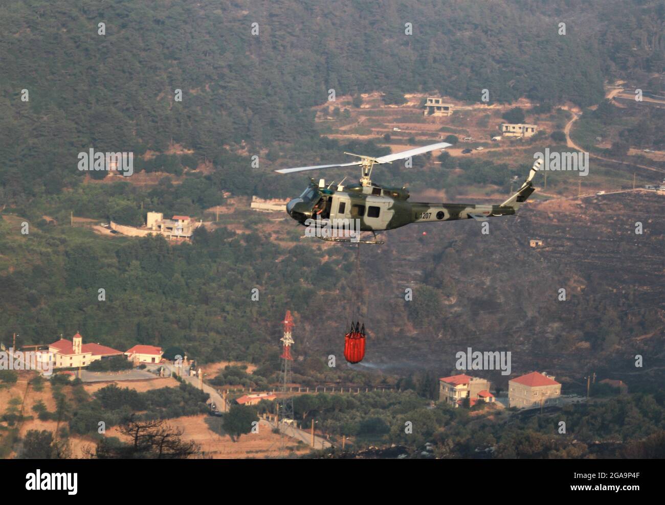 Akkar, Libanon. Juli 2021. Ein Hubschrauber der libanesischen Armee entfacht am 29. Juli 2021 ein Waldfeuer in Akkar, Nordlibanon. Das massive Feuer, das im nordlibanesischen Dorf Quubaiyat ausbrach, wütete in der Region noch am zweiten Tag, berichtete eine lokale Nachrichtenstelle am Donnerstag. Quelle: Khaled/Xinhua/Alamy Live News Stockfoto