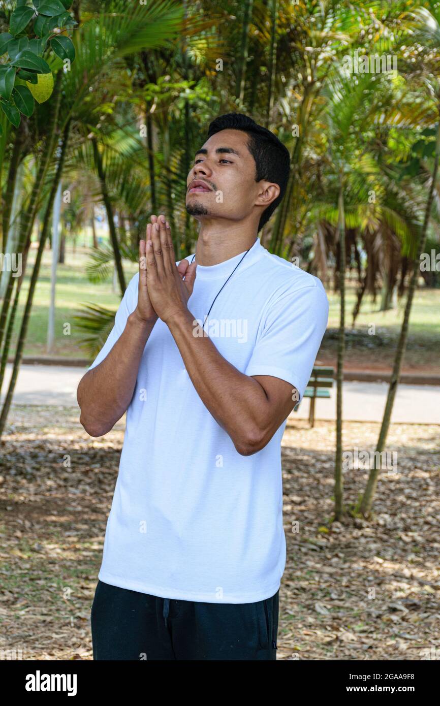 Brasilianischer junger Mann in einem öffentlichen Park, an einem sonnigen Tag, in Grußposition. Stockfoto