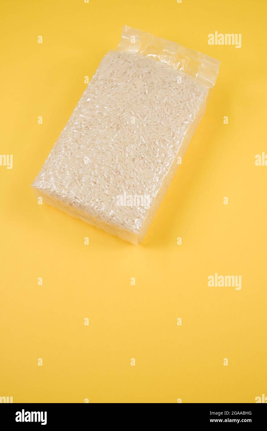 Packung Reiskörner isoliert auf gelbem Hintergrund mit freiem Platz für Text Stockfoto