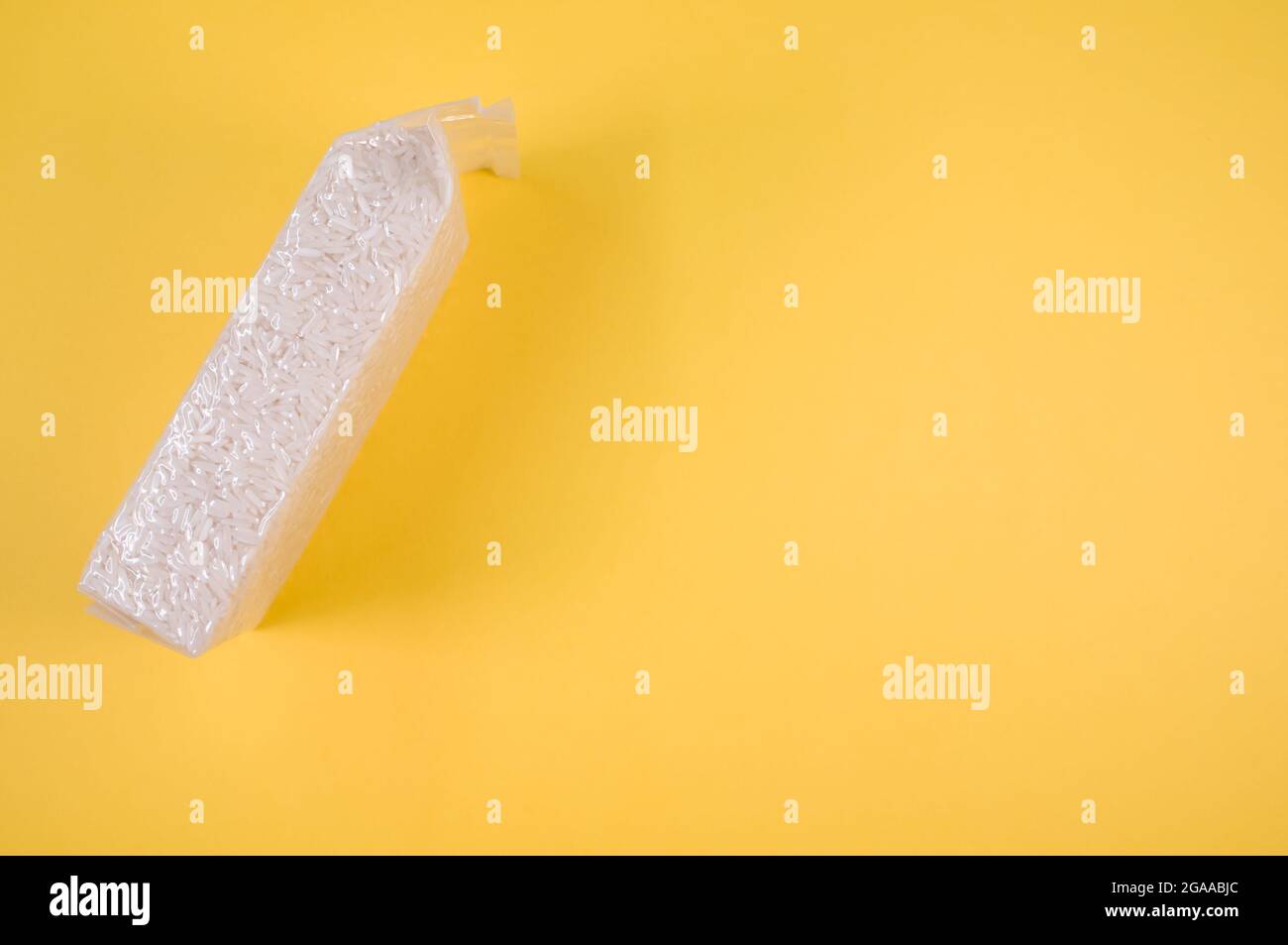 Packung Reiskörner isoliert auf gelbem Hintergrund mit freiem Platz für Text Stockfoto