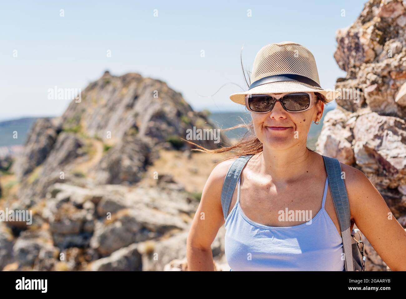 Frau in Sommerkleidung mit Blick auf die Kamera auf der Spitze eines Hügels Stockfoto