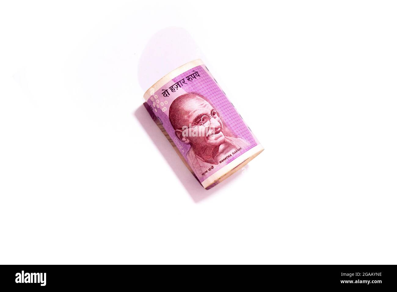 Mahatma Gandhi Porträt in indischen zweitausend Rupien zusammengerollt Banknote isoliert auf weißem Hintergrund. Stockfoto