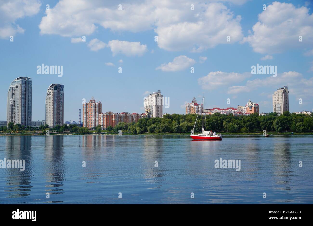 Panorama der Kiewer Stadtlandschaft des Flusses Dnipro. Modernes Wohngebäude, Yacht und Park mit urbaner Straßenlandschaft am Fluss. Stockfoto
