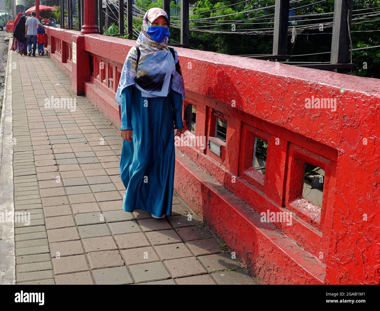 Eine muslimische Frau trägt eine Gesichtsbedeckung und geht allein auf einer Brücke. Stockfoto