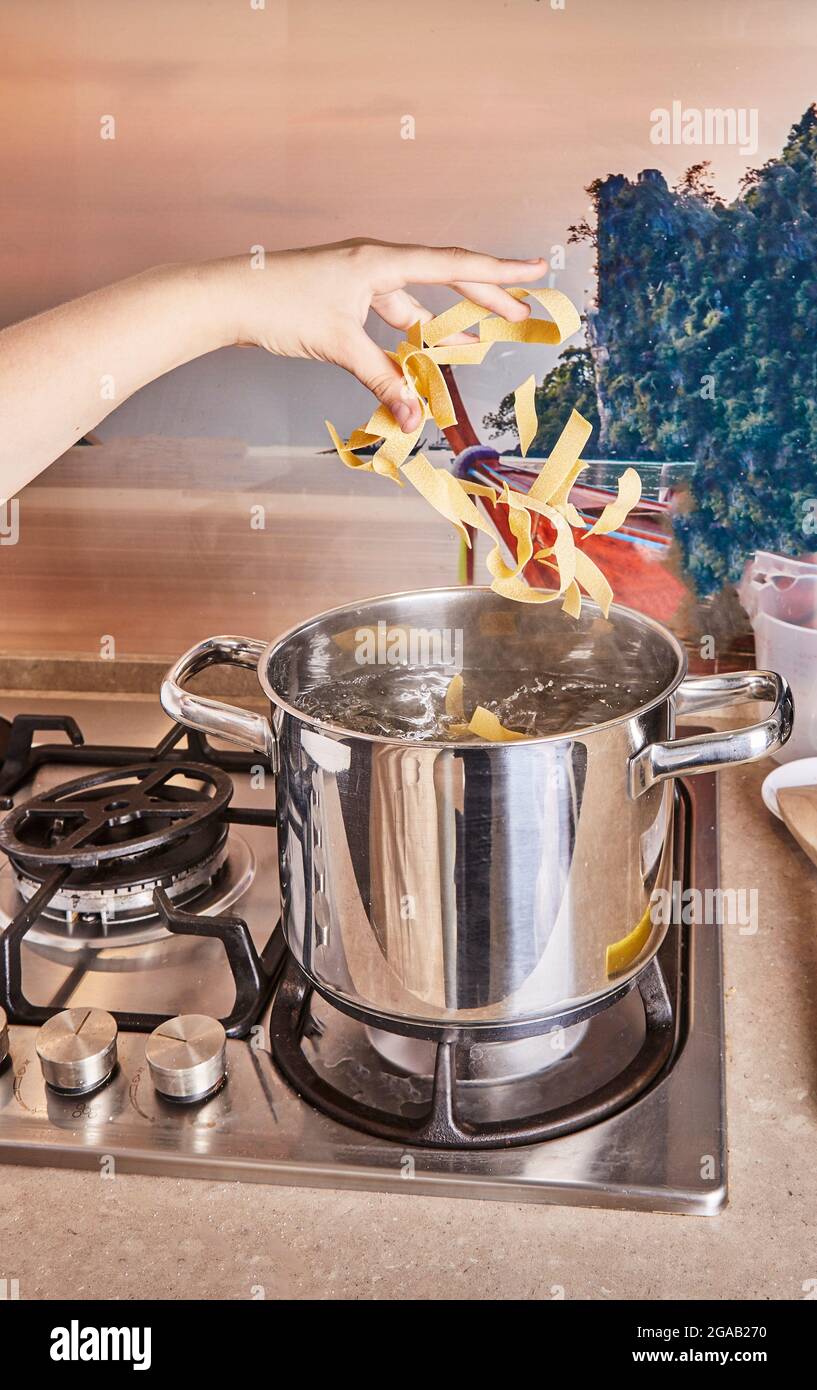 Teenager warfen Pasta mit Rezept aus dem Internet in kochendes Wasser für Spaghetti Bolognese Stockfoto