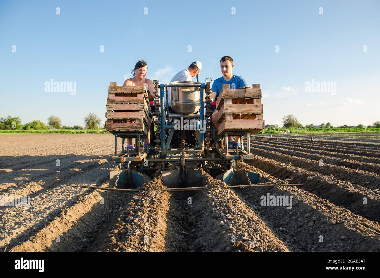 Arbeiter auf einem Traktor Pflanzen Kartoffeln an. Automatisierung des Prozesses der Pflanzung von Kartoffelsamen. Hohe Effizienz und Geschwindigkeit. Landwirtschaftliche Technologien. Stockfoto