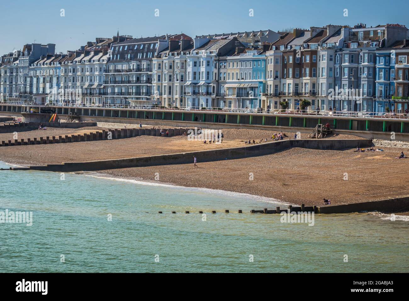 Am Meer in Hastings im Vereinigten Königreich. Viktorianische Reihenhäuser säumen die Straßen mit der Promenade und dem Strand und dem Meer im Vordergrund. Stockfoto