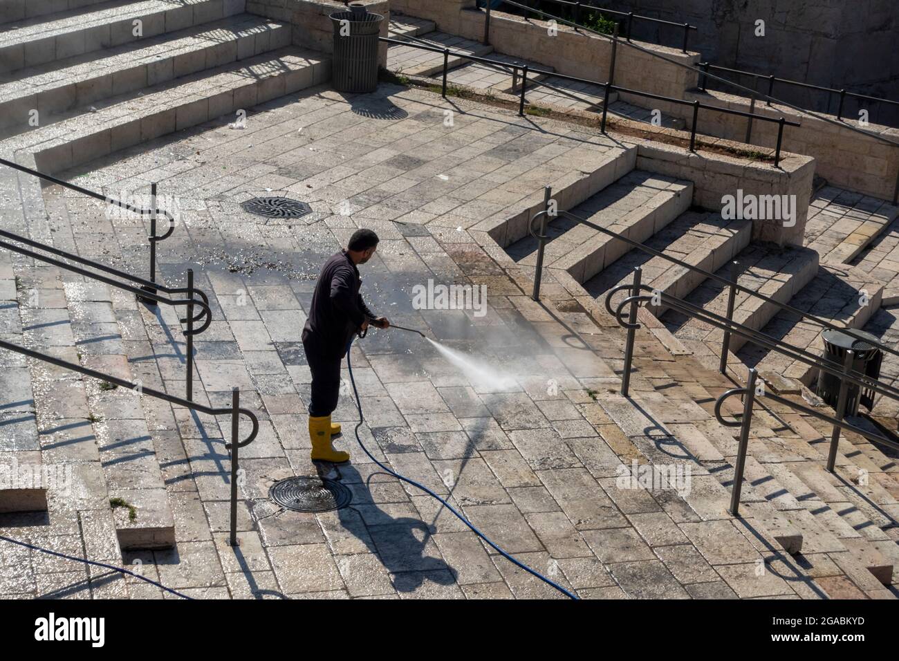 Ein israelisch-arabischer Gemeindearbeiter reinigt die Treppen des Damaskus-Tors (Bab al-Amoud), eines der Haupttore, das zum Tempelberg in der Altstadt Ost-Jerusalems führt Stockfoto