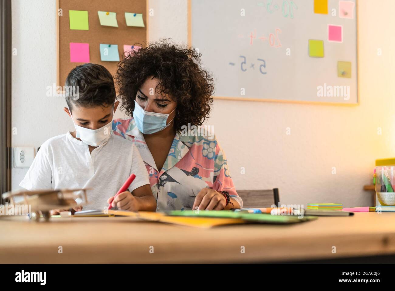 Lehrerin mit Kinderzeichnung im Vorschulunterricht, während sie Gesichtsschutzmaske während einer Corona-Virus-Pandemie trägt Stockfoto