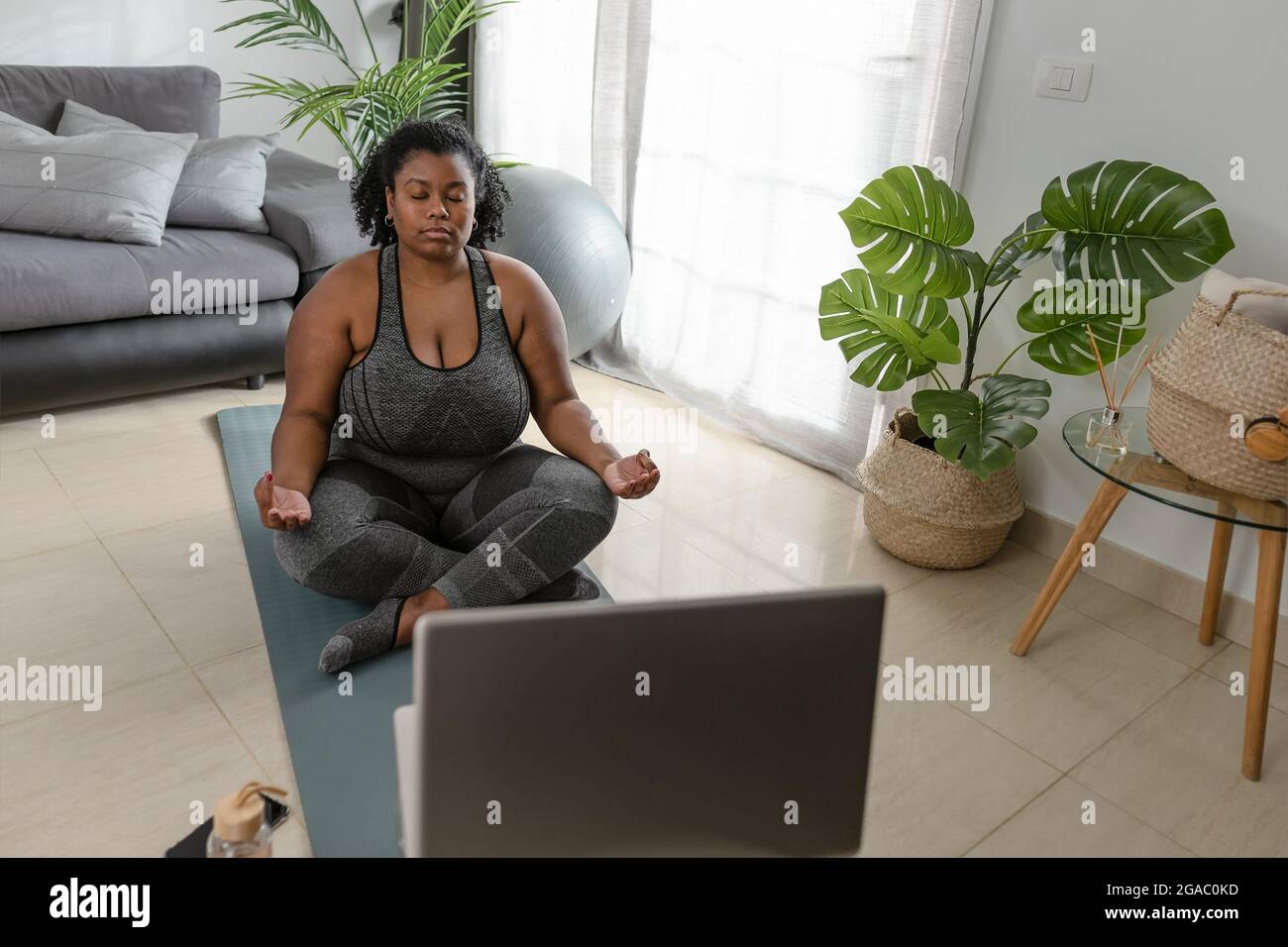 Junge afrikanische kurvige Frau macht Yoga virtuelle Fitness-Klasse mit Laptop zu Hause - Sport Wellness Menschen Lifestyle-Konzept Stockfoto