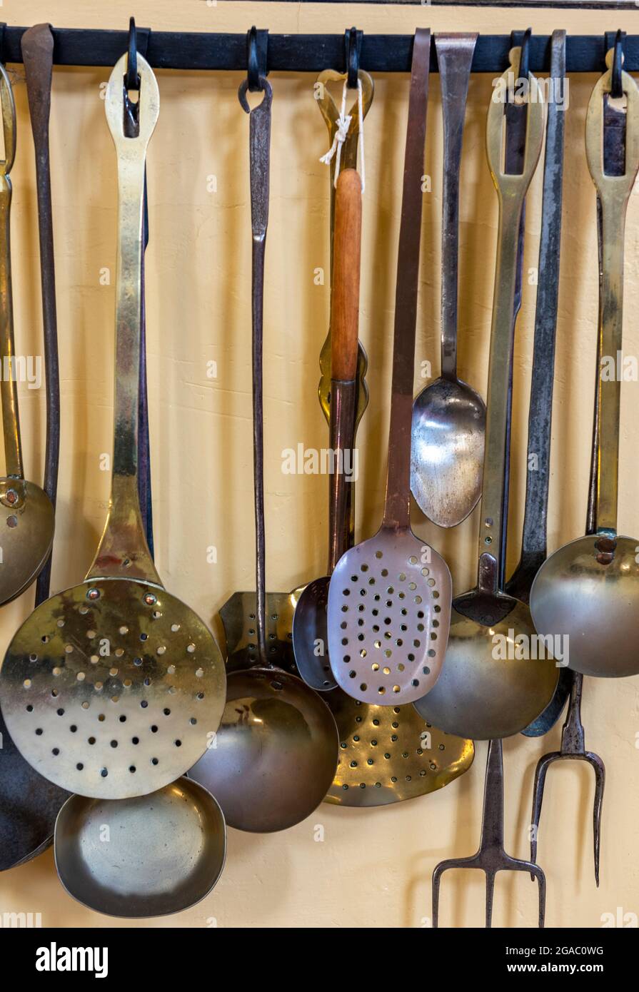 Auswahl an alten oder antiken Kochutensilien, die in einer viktorianischen oder edwardianischen Landküche auf einem Regal hängen Stockfoto