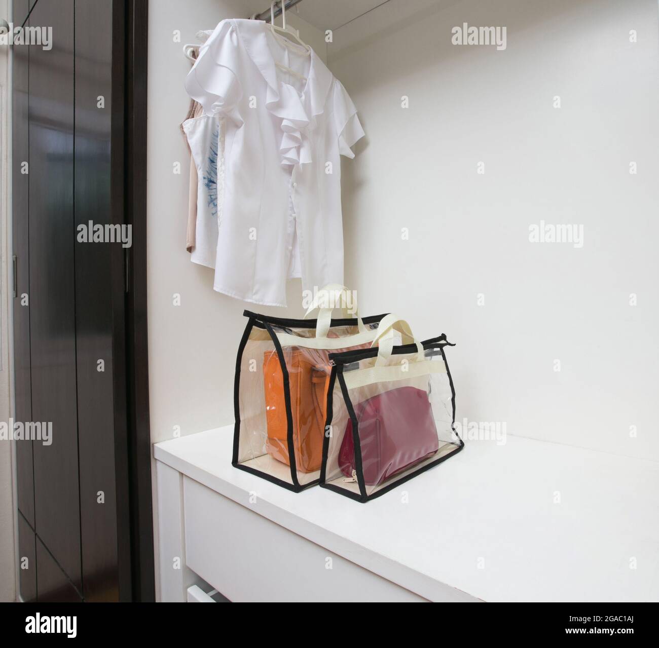 Offener weißer Schrank mit Kleidung und Taschen und leerem Platz Stockfoto