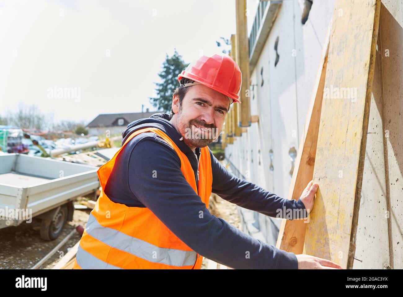 Zimmermannsfachmann mit rotem Hut auf der Schale einer Baustelle aus dem Hausbau Stockfoto