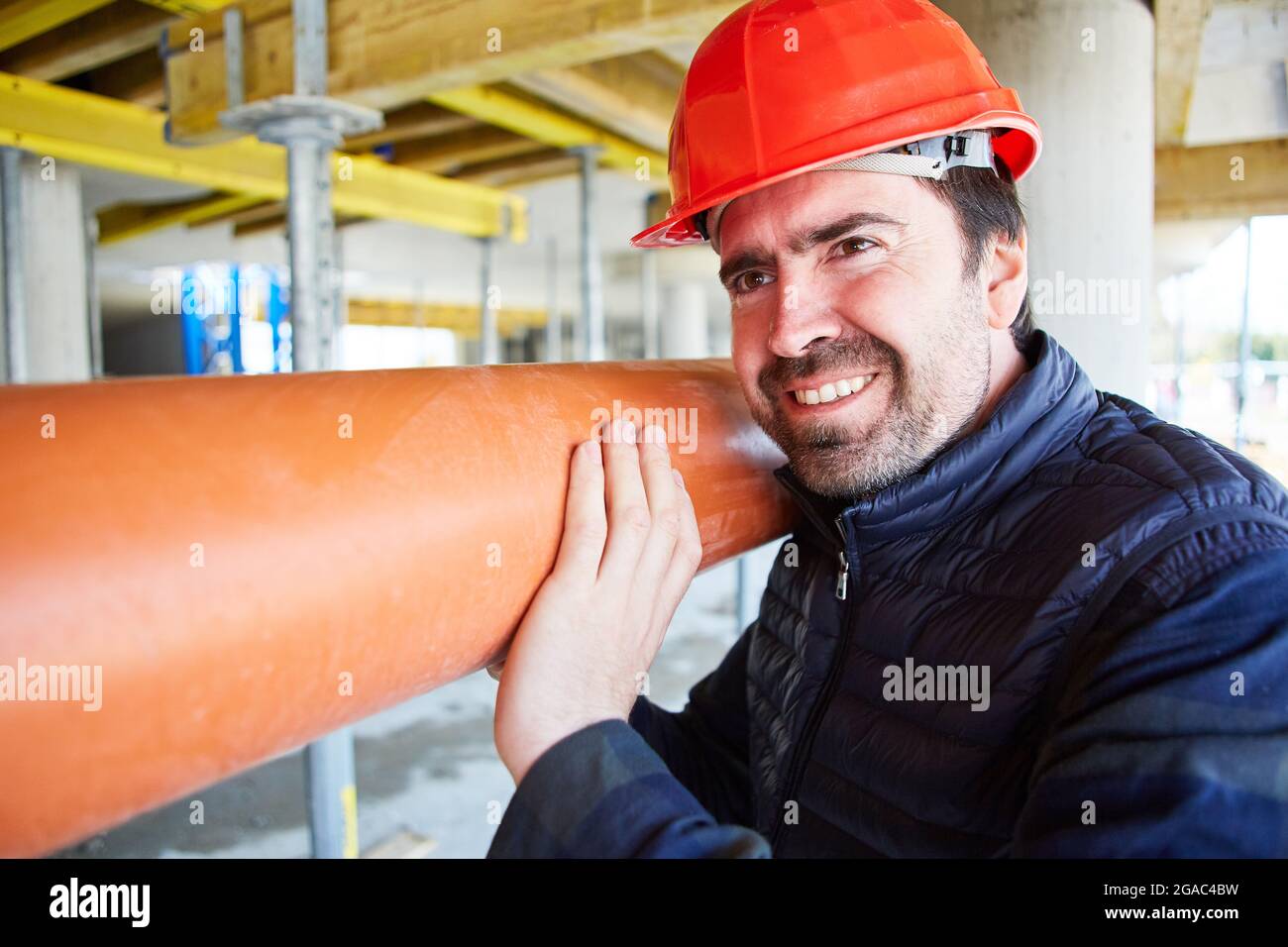 Handwerker oder Arbeiter auf der Baustelle in der Gebäudehülle tragen ein Abflussrohr zur Montage Stockfoto