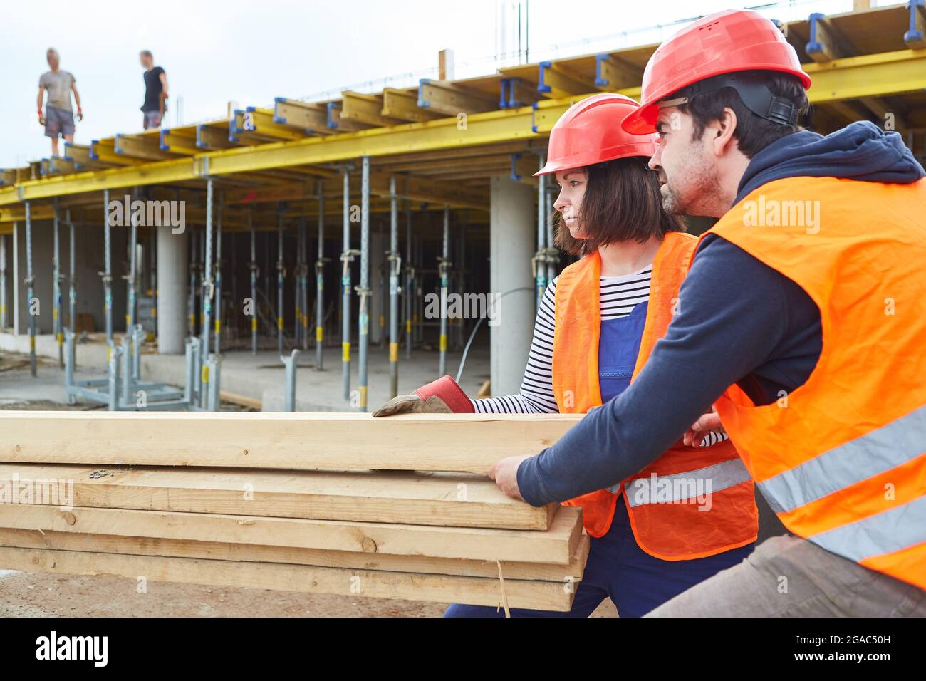 Arbeiter- oder Handwerkerteam transportiert Holz vom Hausgebäude zur Schalenbaustelle Stockfoto