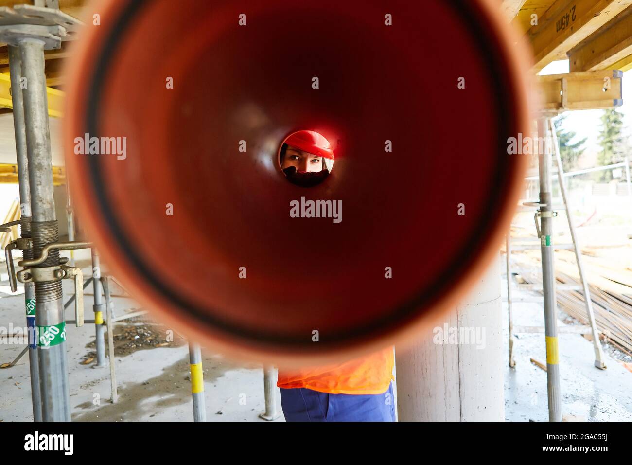 Handwerker schaut bei der Montage in der Schale einer Baustelle durch ein Abflussrohr Stockfoto