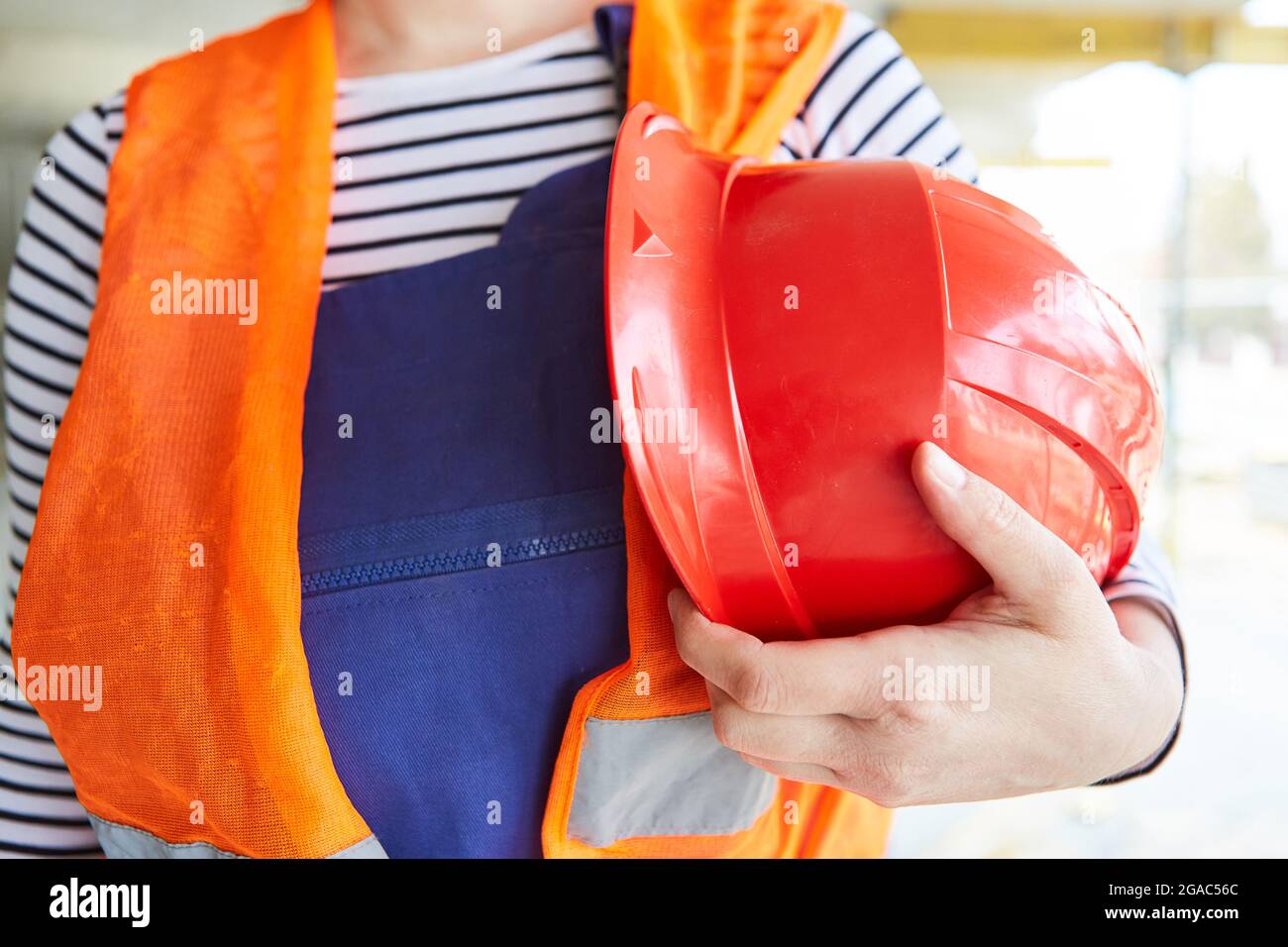 Selbstbewusster Bauarbeiter mit reflektierender Kleidung und Schutzhelm auf  einer Baustelle, lizenzfreies Stockfoto