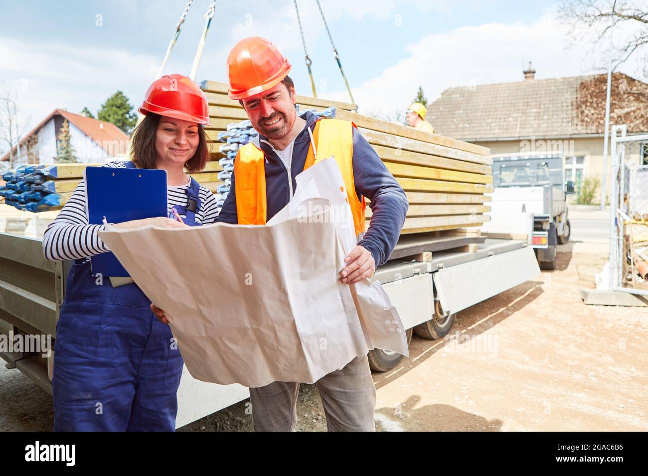 Architekten-Team mit Blaupause vor einem LKW mit Materiallieferung auf der Baustelle des Hausbaus Stockfoto