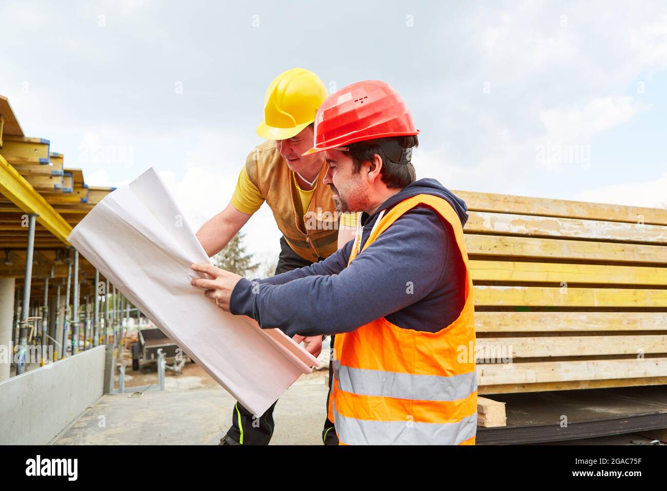 Architekt und Handwerker mit Bauplan auf der neuen Baustelle zusammen bei der Bauplanung Stockfoto