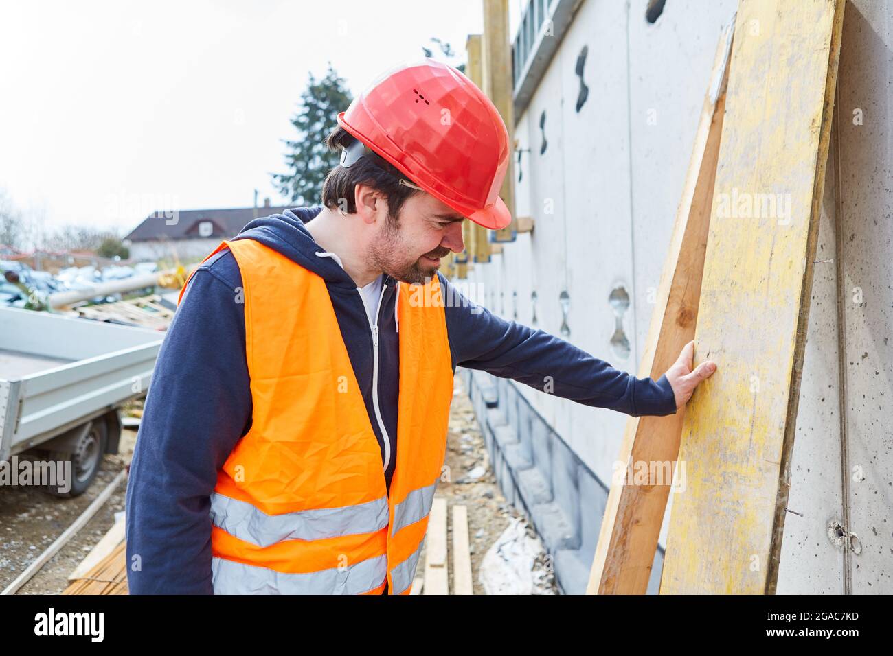 Handwerker oder Bauarbeiter mit rotem Hut steuert die Schale einer Baustelle Stockfoto