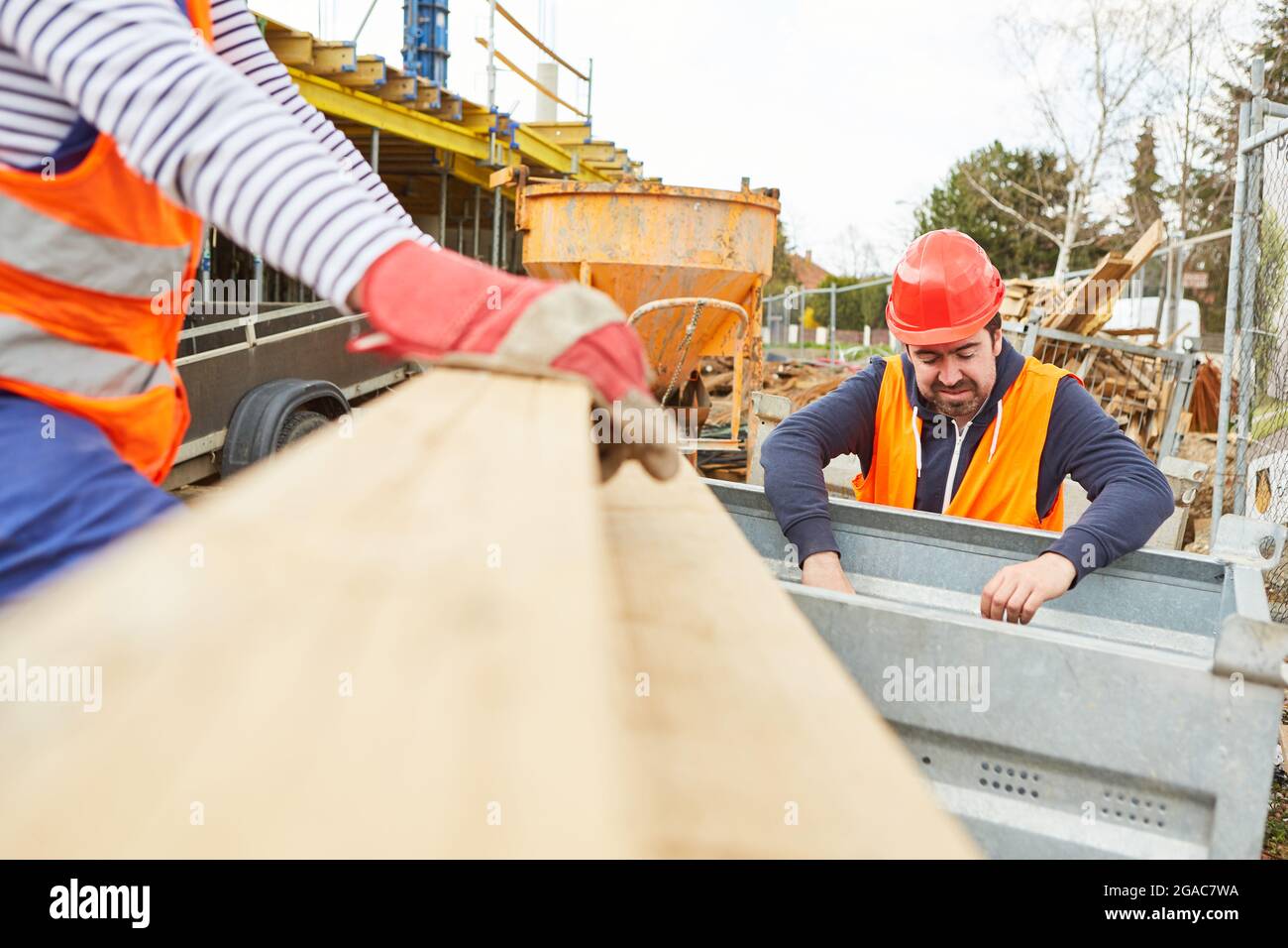 Bauarbeiter entladen gemeinsam Holz als Baumaterial für die Baustelle des Hausgebäudes Stockfoto