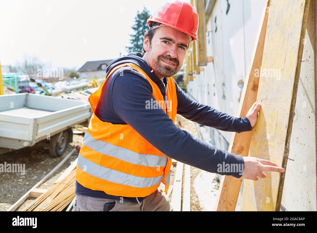 Handwerker als Zimmermann oder Vorarbeiter mit Holz als Baustoff auf der Baustelle des Hausbaus Stockfoto