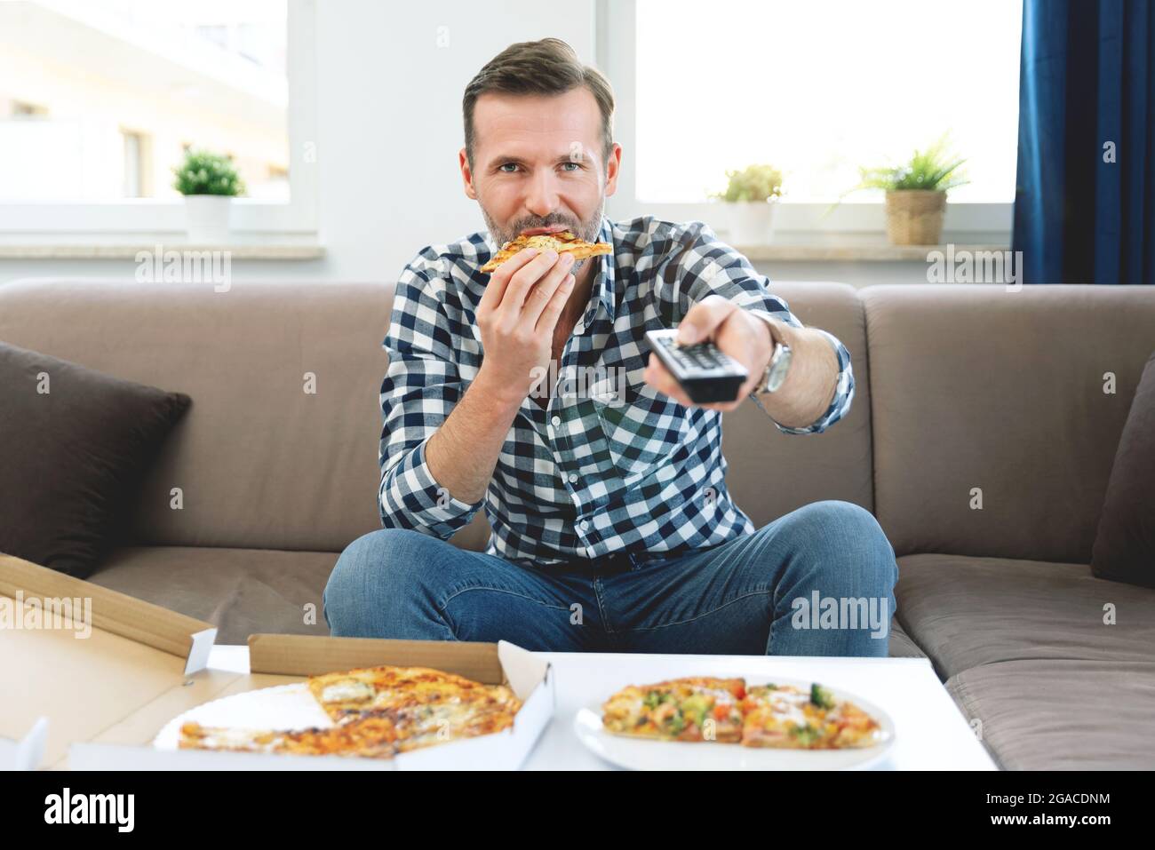 Mann, der beim Pizza-Essen Fernsehen schaute. Freizeit zu Hause verbringen Stockfoto