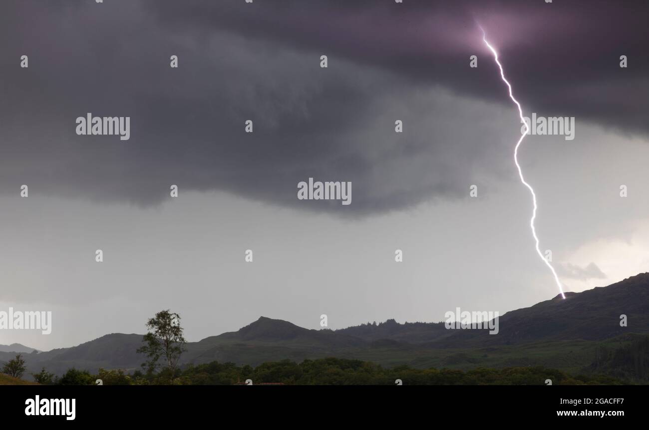 Ein Bild von einem einzigen Blitzschlag auf der Seite eines Berges, der von einer Wolke zur anderen ableuchtet Stockfoto