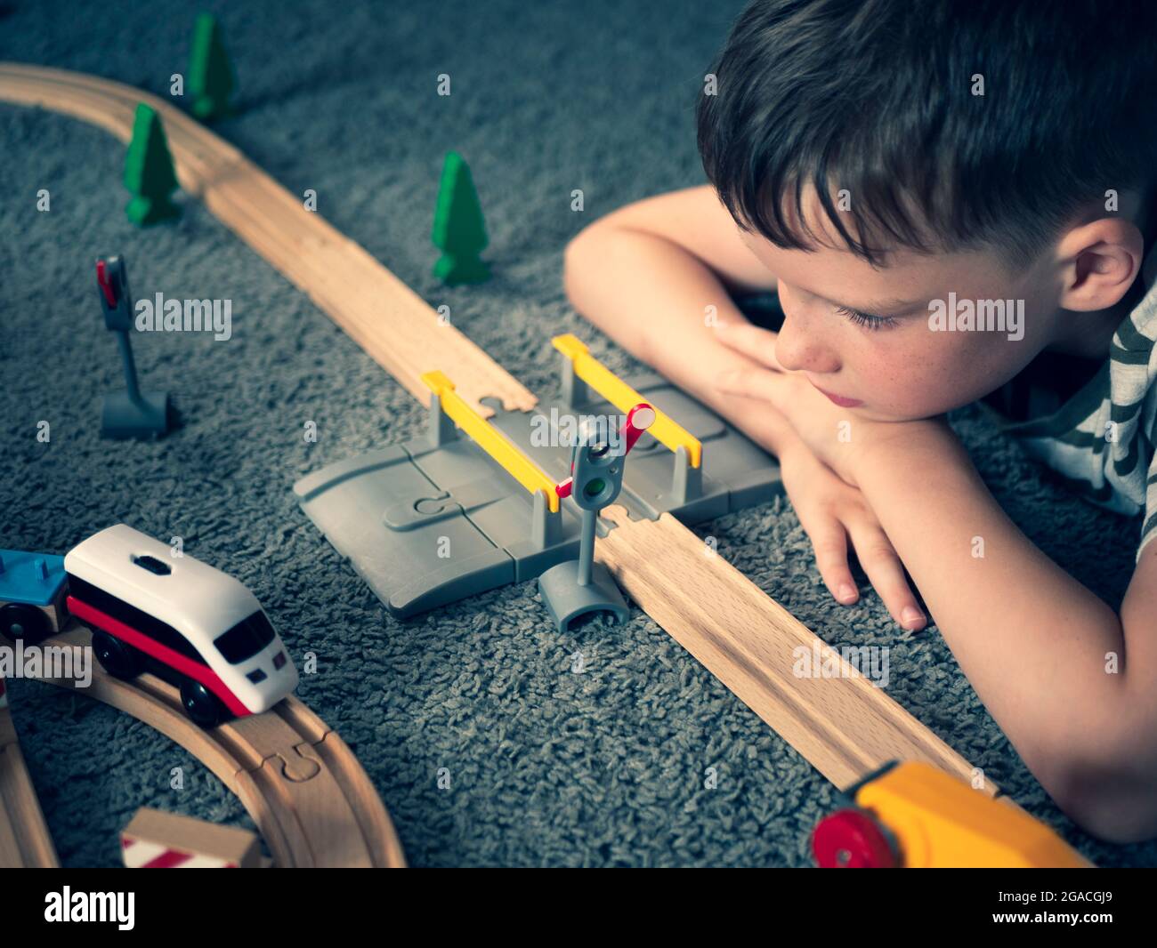 Boy beobachtet den laufenden Spielzeugzug. Holzspielzeugeisenbahn und Kindergesicht. Konzept der Kindheit, Spiele für Kinder Stockfoto