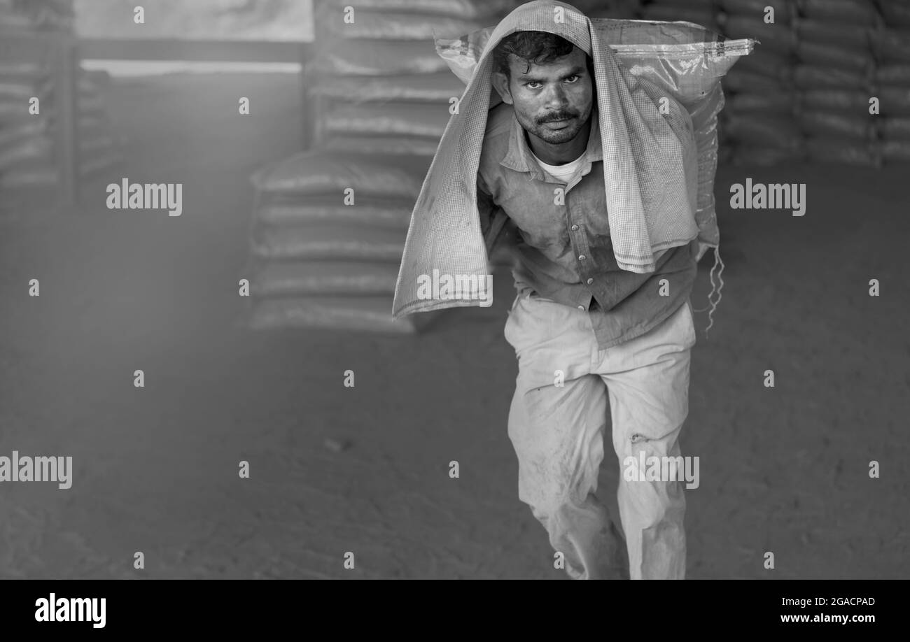 Man labors, um Zementbeutel unter staubigen Bedingungen aus dem Zug in heißen Sommerbedingungen in Mathura, Uttar Pradesh, Indien zu entladen. Stockfoto