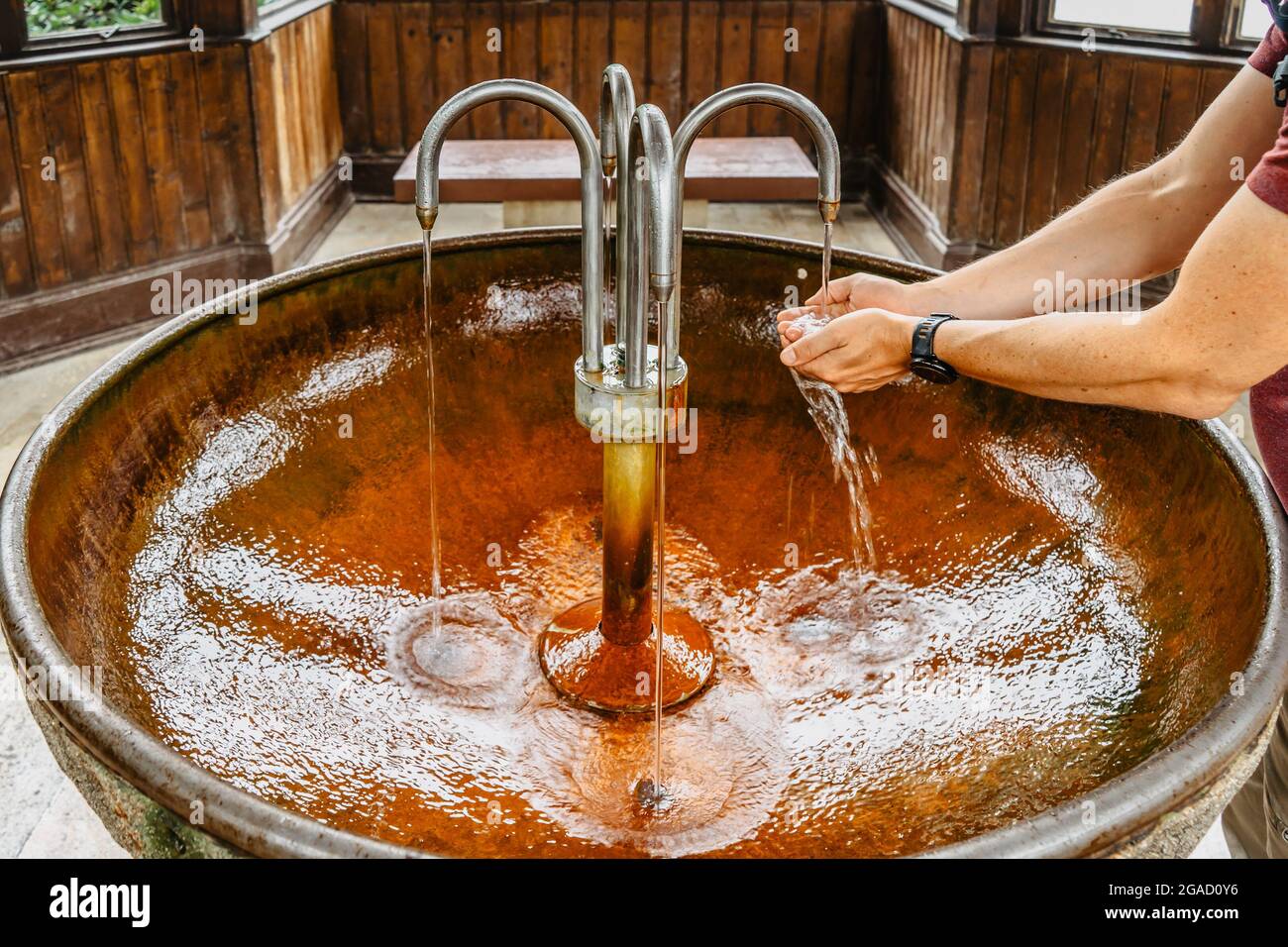Nahaufnahme der männlichen Hände mit therapeutischem Mineralwasser aus der Heilquelle in Karlova Studanka, Tschechische Republik. Gesundes reines Wasser in der berühmten Kurstadt. Stockfoto