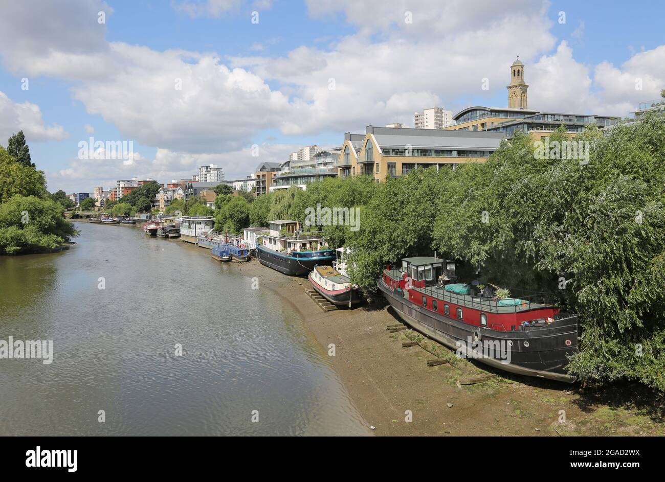 Hausboote liegen am Nordufer der Themse westlich der Kew Bridge, London, Großbritannien. Die Rümpfe ruhen auf Timver-Strahlen, um sie bei Ebbe auf dem Niveau zu halten. Stockfoto