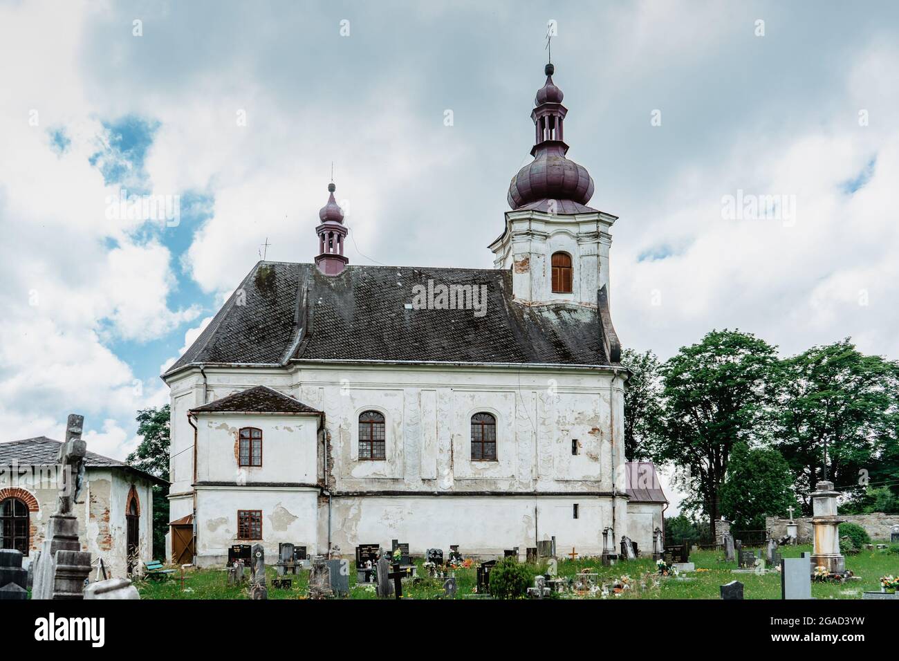 Puste Zibridovice, Tschechische Republik - Juli 12,2021. Weiße alte barocke Kirche der Heiligen Maria Magdalena mit Glockenturm und Friedhof in einem kleinen tschechischen Dorf Stockfoto