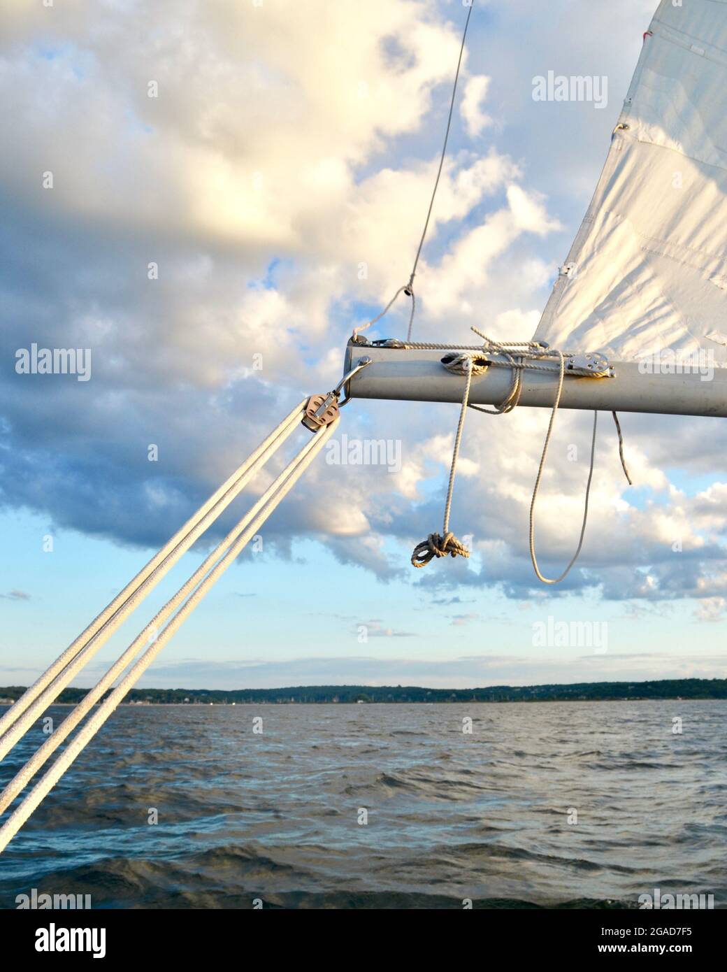 Eine einzigartige Ansicht des Hauptblatts eines Segelbootes, das mit dem Boom verbunden ist. Im Hintergrund ein entferntes Ufer und dramatische, schwerfällig Wolken. Stockfoto